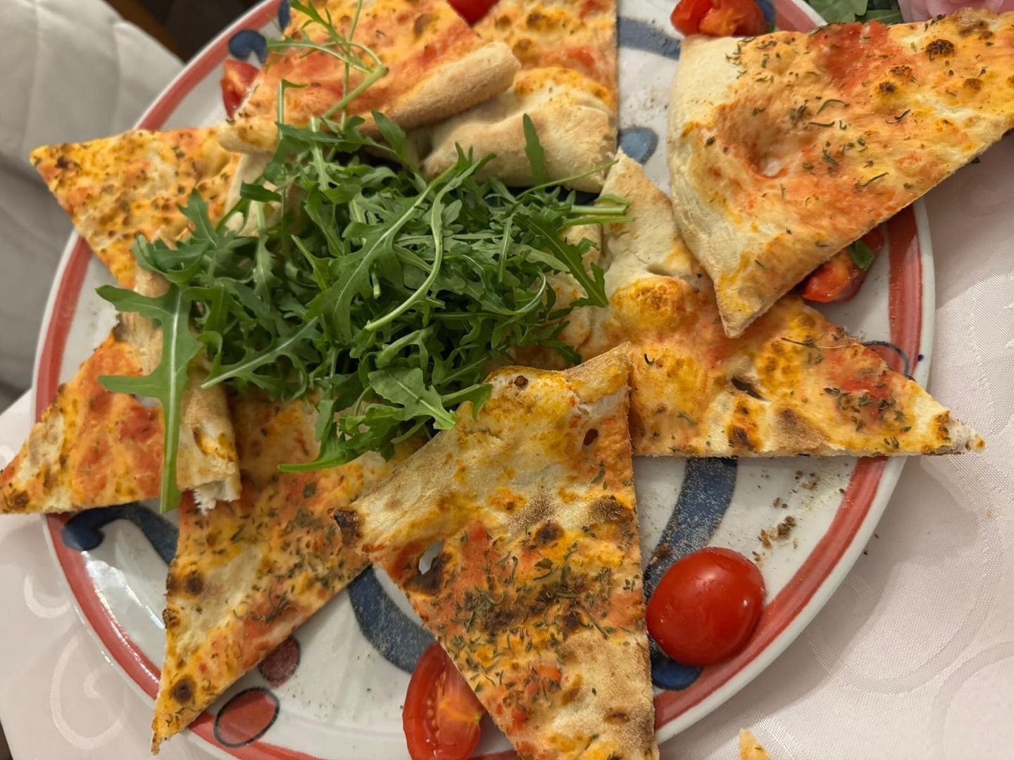 Teller mit Focaccia-Scheiben, Tomaten und Rucola.