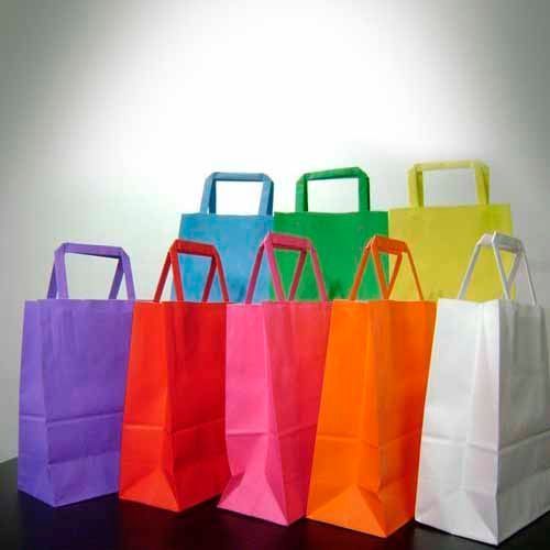 Bolsas de papel de colores con asas rectangulares sobre una mesa sobre un fondo blanco.