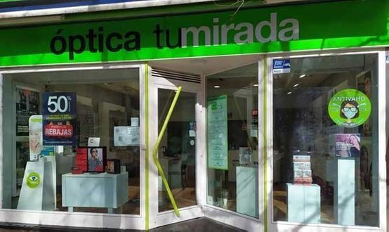 Un frente de tienda con un letrero verde que dice Óptica Tumirada