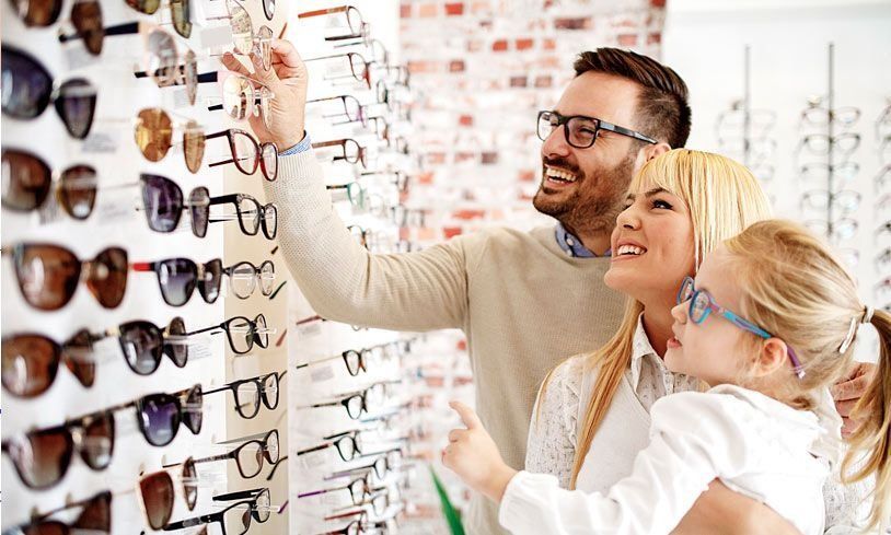 Una familia está mirando gafas de sol en una óptica.
