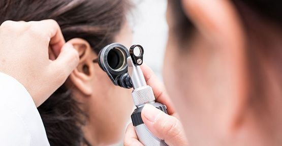 Un médico está examinando el oído de un paciente con un otoscopio.