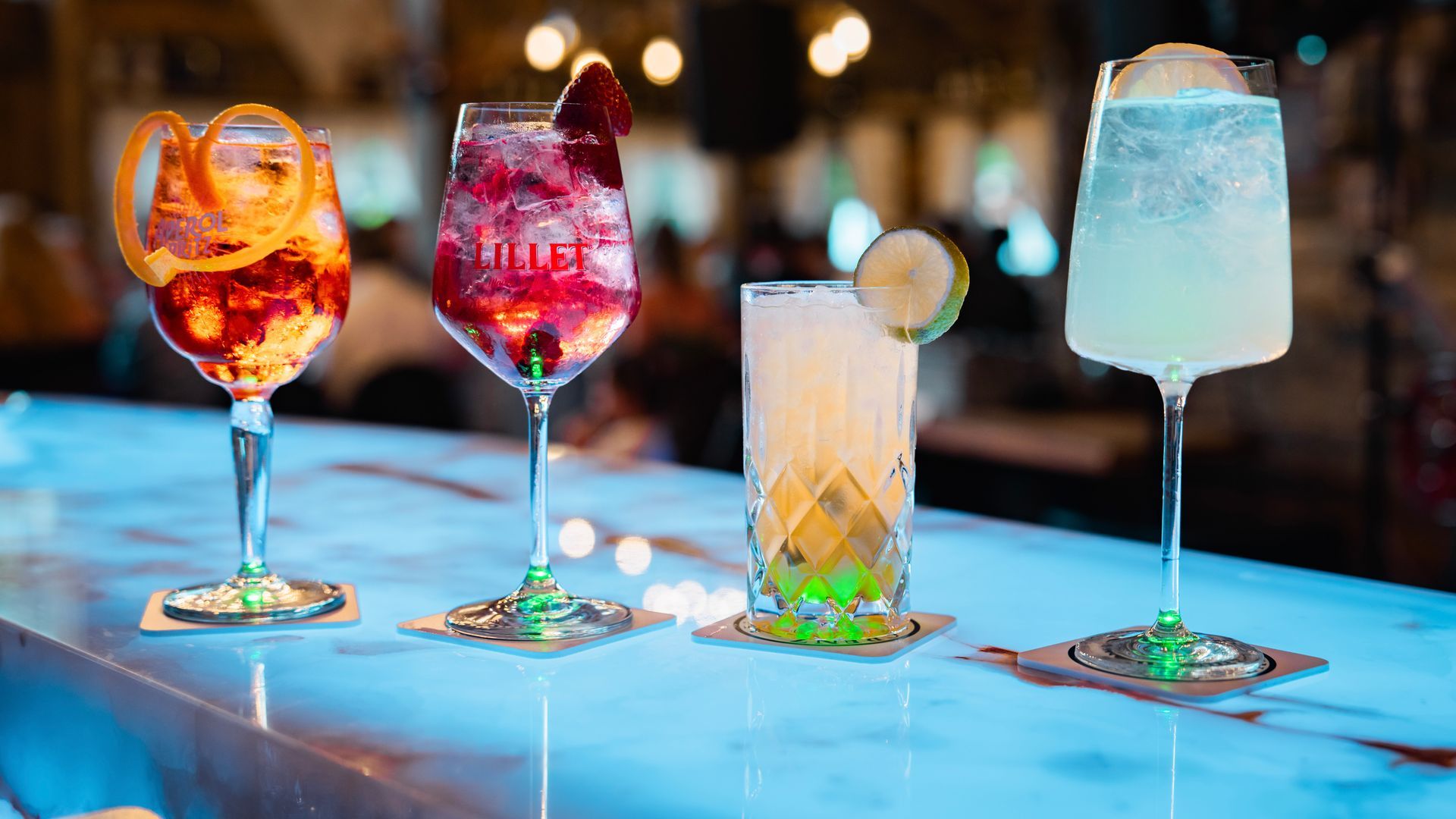 Bunte Cocktails mit Dekoration auf beleuchtetem Tresen