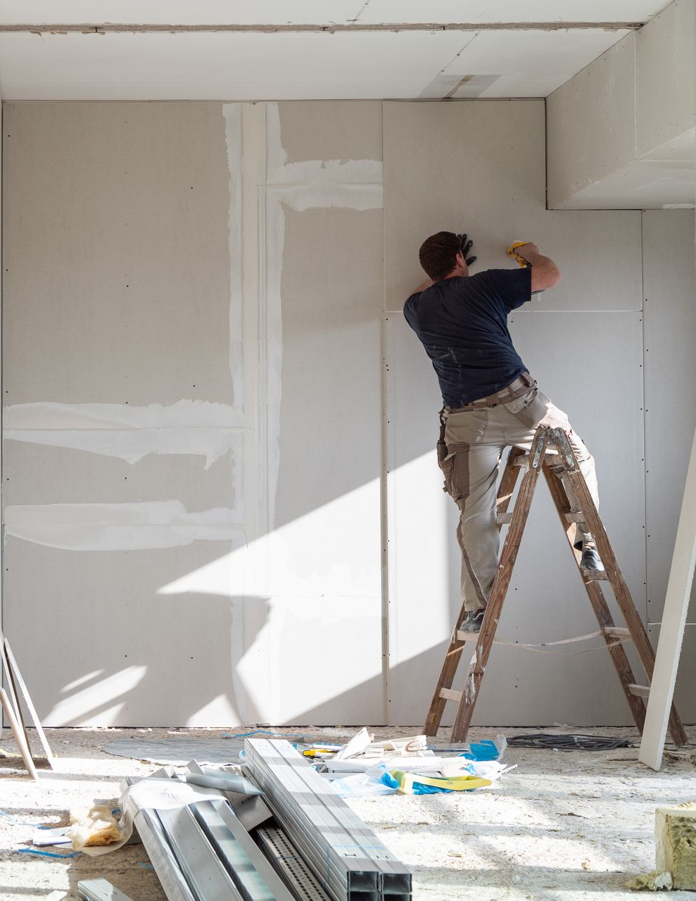 Homme posant une plaque de plâtre sur un mur