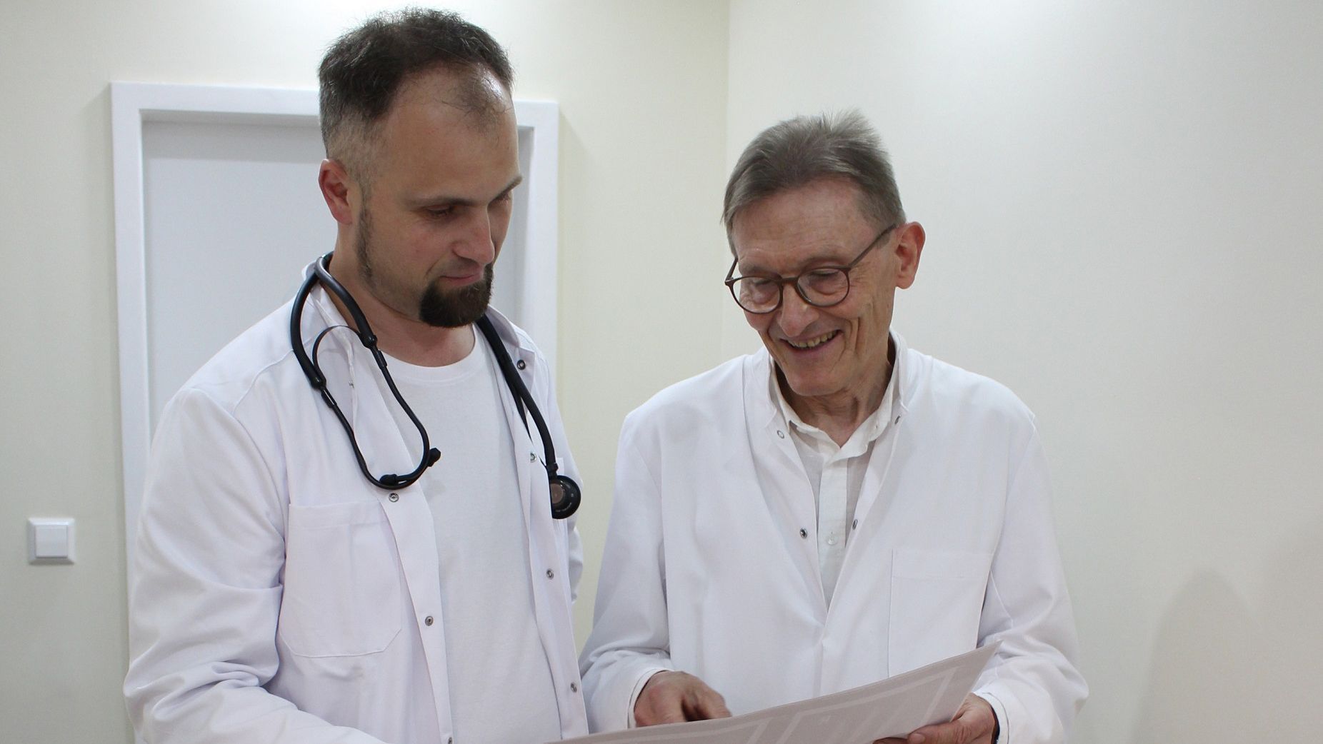 Zwei Ärzte schauen sich gemeinsam ein Blatt Papier an.