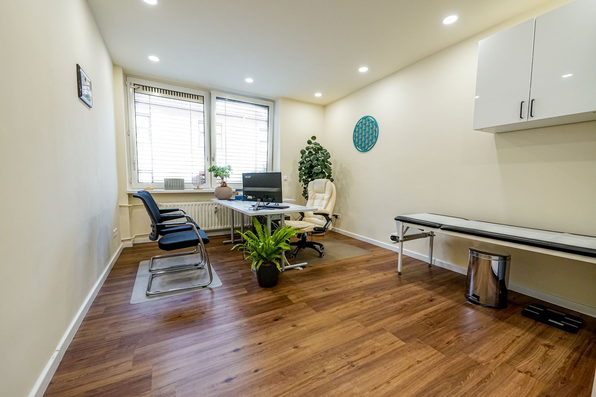 Ein Beratungszimmer mit Holzboden, einem Schreibtisch, Stühlen und einem Computer.