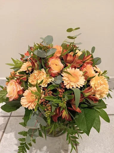Composition florale, pêche et orange dans un vase en verre transparent.