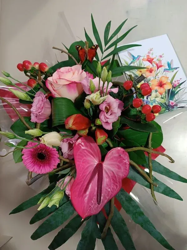 Bouquet de fleurs rose et rouge, accompagné d'une carte ornée de colibris et de fleurs tropicales.