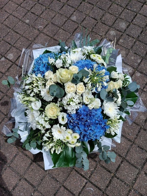 Bouquet de fleurs bleues et blanches sur un pavé.