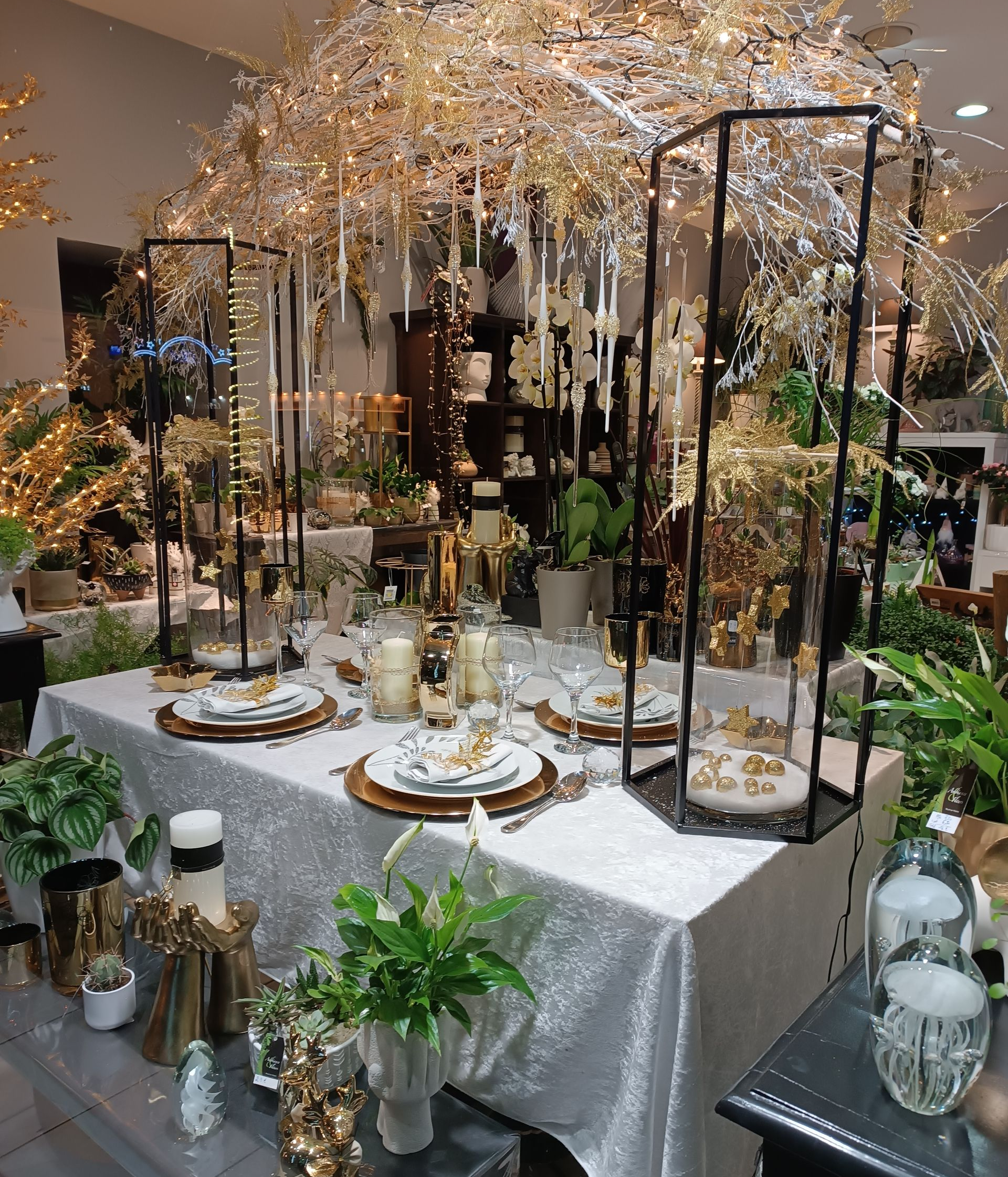 Élégante table à manger ornée de décorations dorées et blanches, sous un dais doré et scintillant.