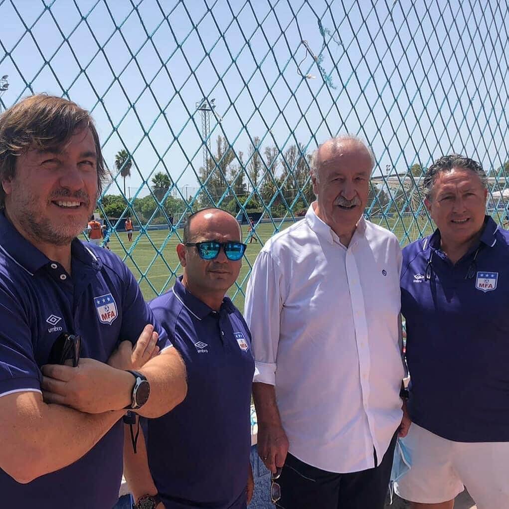 Un grupo de hombres posa para una fotografía frente a una valla de alambre.