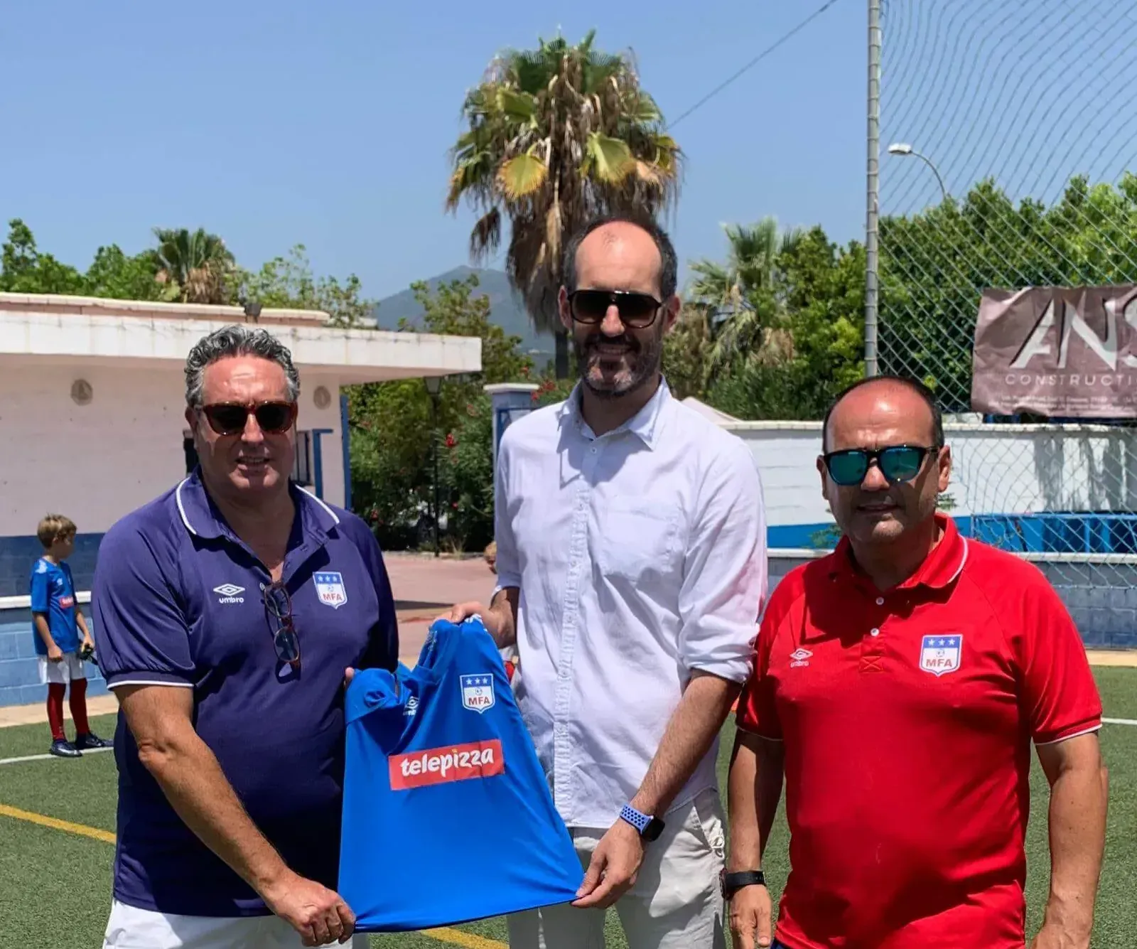 Tres personas sosteniendo una camiseta de fútbol