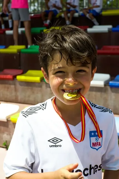 Un niño pequeño lleva una medalla alrededor de su cuello y sonríe.