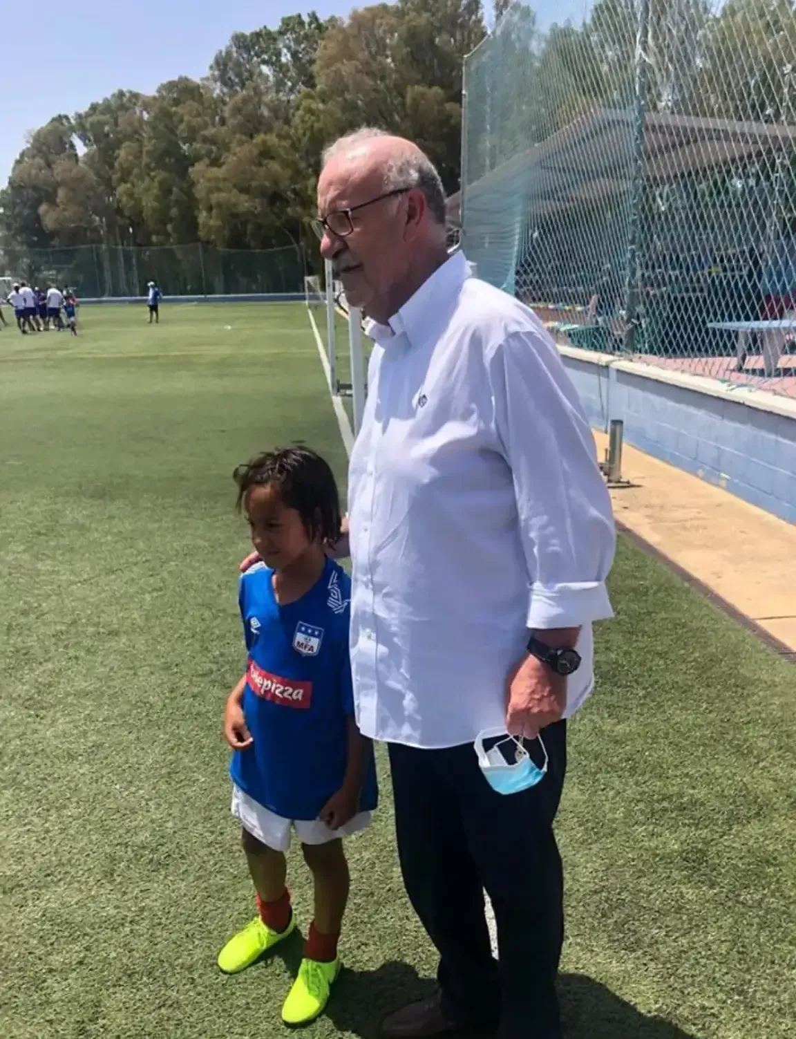 Un hombre y un niño están parados en un campo de fútbol.