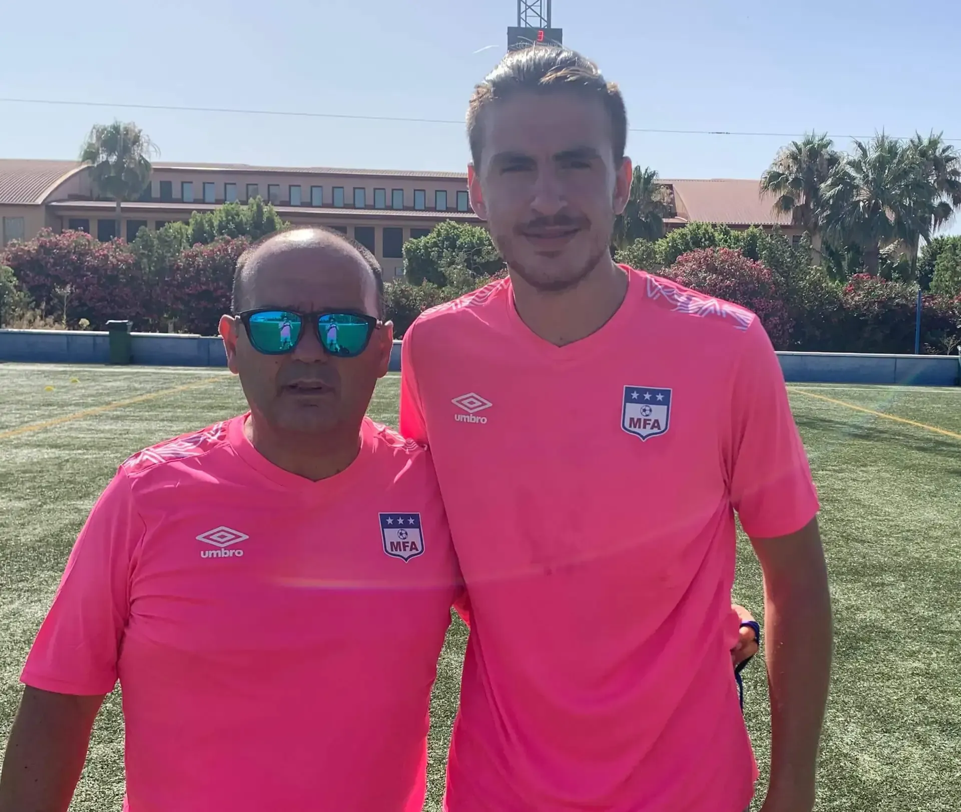 Dos hombres con camisas rosas posan para una foto.