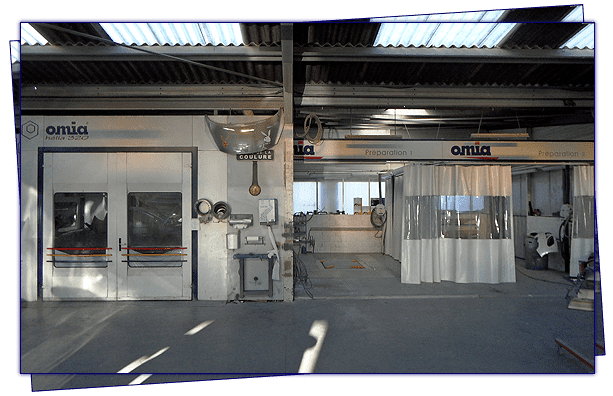 Intérieur d'un atelier de réparation automobile avec cabine de peinture, espace ouvert et éclairage zénithal.