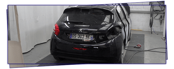 Voiture noire avec des dégâts à l'arrière dans un atelier de réparation.