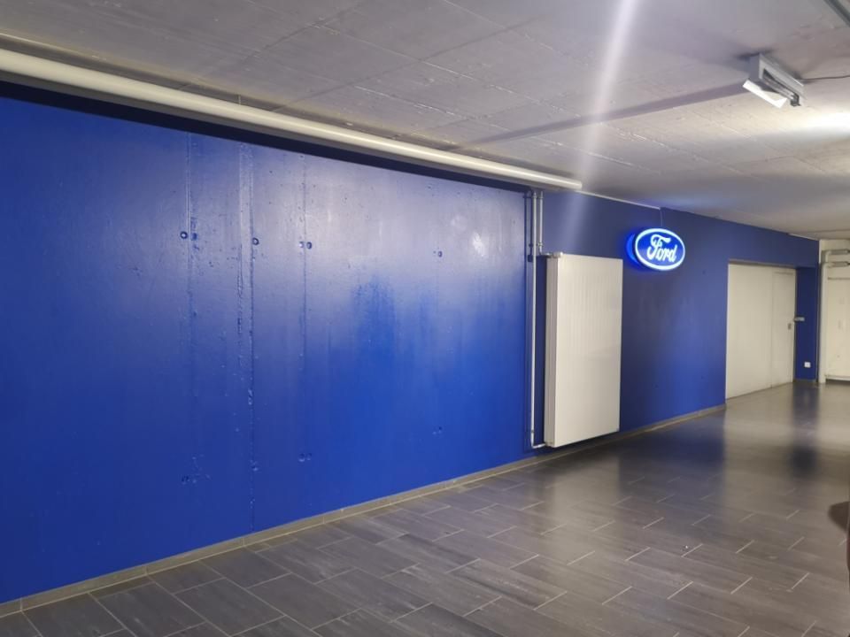 Blauer Flur mit geschlossenen Türen und einem leuchtenden ovalen Schild an der Wand