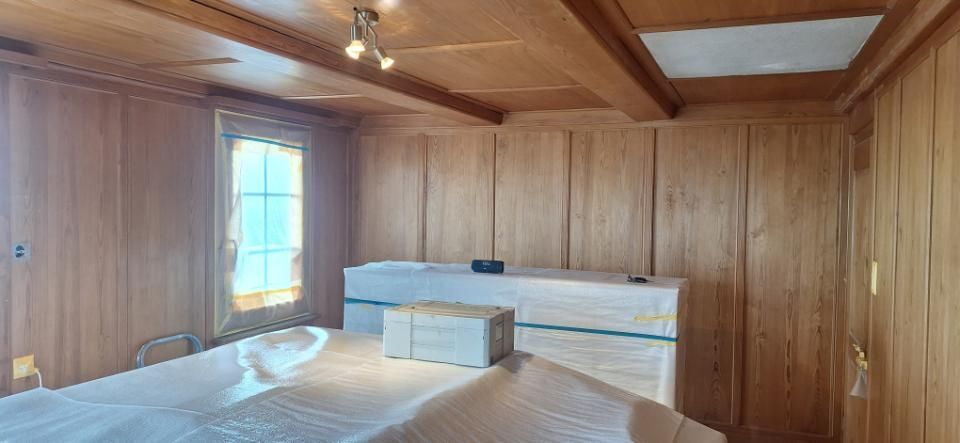 Holzgetäfelter Raum mit Oberlichtern, einem Fenster und einem niedrigen Bett oder einer Plattform im Vordergrund