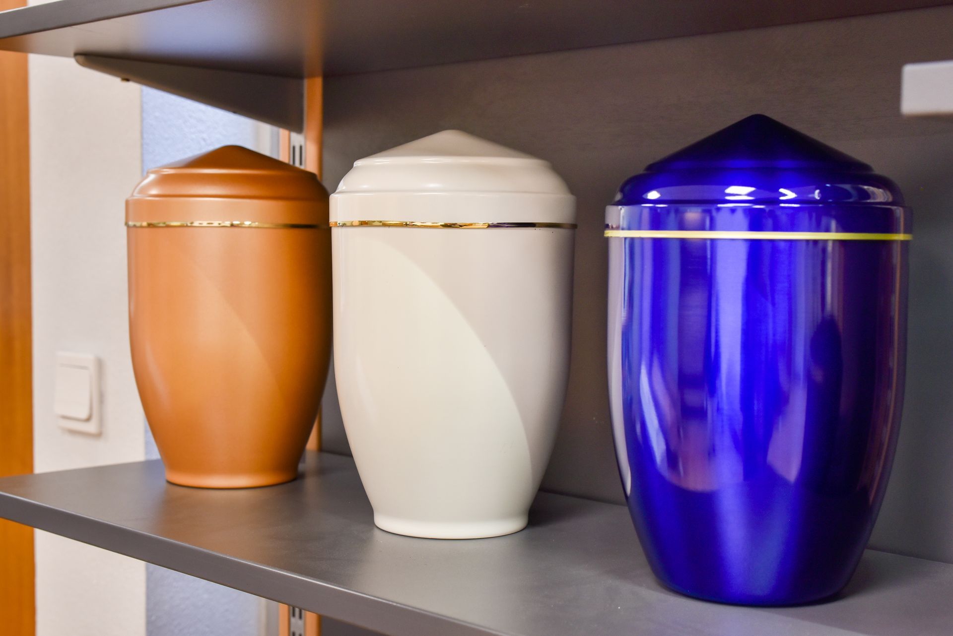 Trois urnes décoratives en cuivre, blanc et bleu sur une étagère