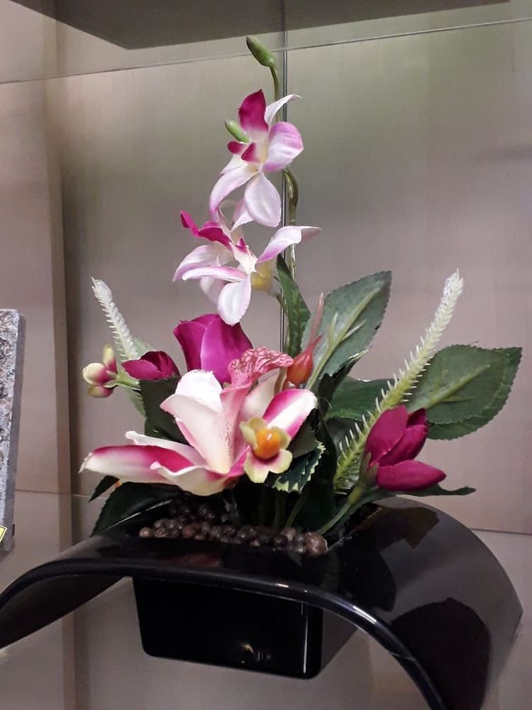 Composition florale rose et blanche dans un vase noir sur un comptoir