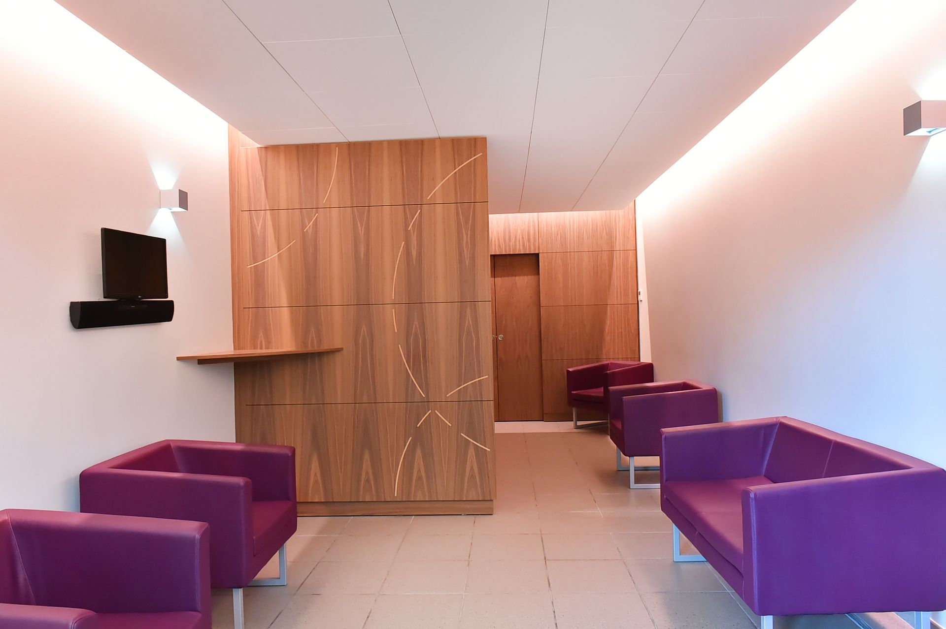 Hall d'entrée moderne avec chaises violettes, murs lambrissés et appliques murales à l'éclairage chaleureux