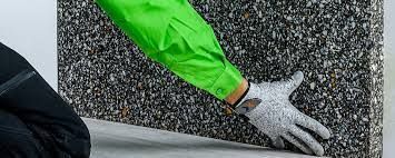 Una persona que lleva guantes sostiene un trozo de hormigón.