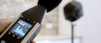 Una persona sostiene un medidor de sonido en su mano frente a un micrófono.