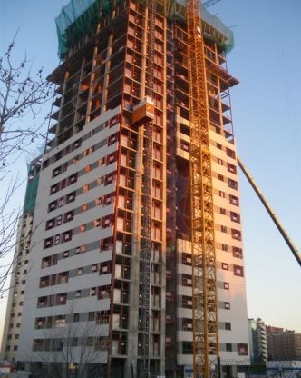 Un edificio alto en construcción con una grúa delante.