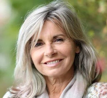 Una mujer con cabello gris sonríe para la cámara.