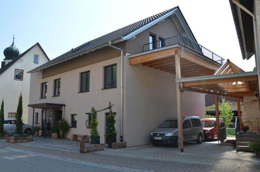 Zwei Autos stehen vor einem Haus mit Carport