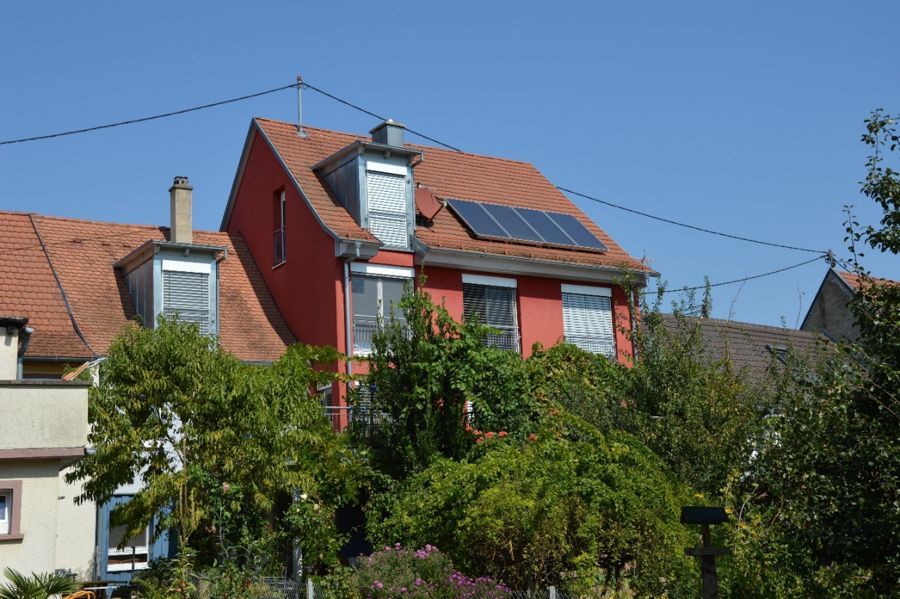 Ein rotes Haus mit Sonnenkollektoren auf dem Dach