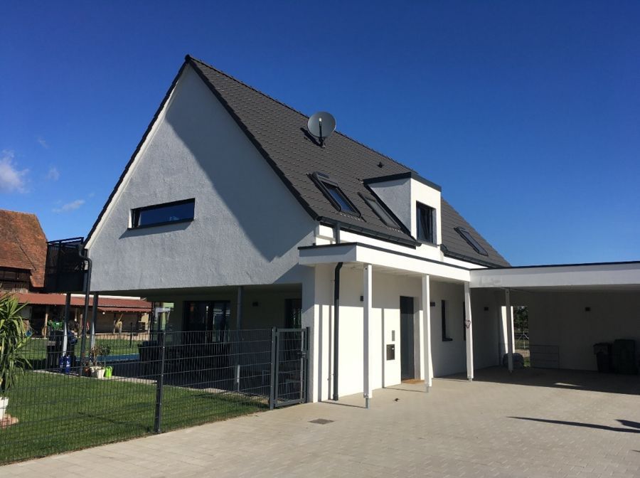 Ein weißes Haus mit grauem Dach und Carport