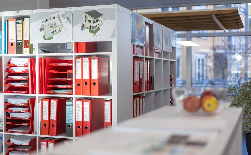 Eine Reihe von Regalen, gefüllt mit roten Ordnern und Papieren.