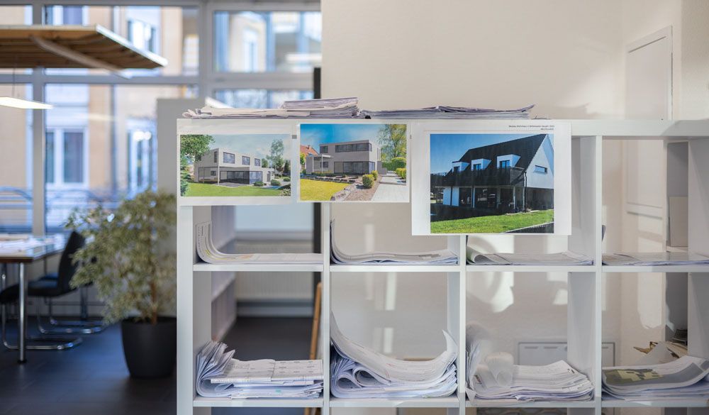 Ein Regal mit Bildern eines Hauses darauf in einem Büro.