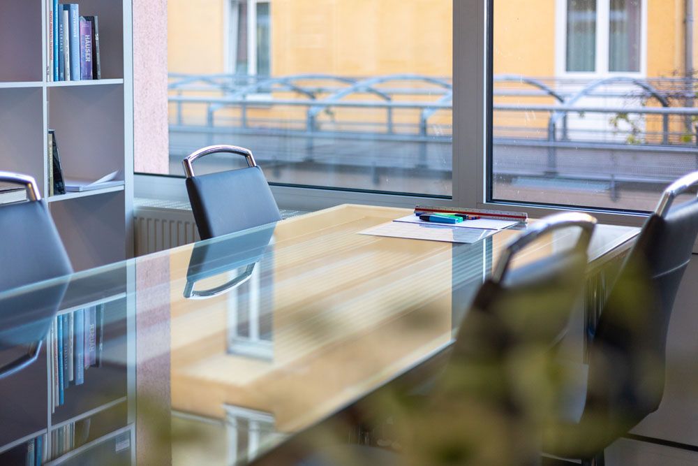 Ein Konferenzraum mit einem Glastisch und Stühlen vor einem Fenster.