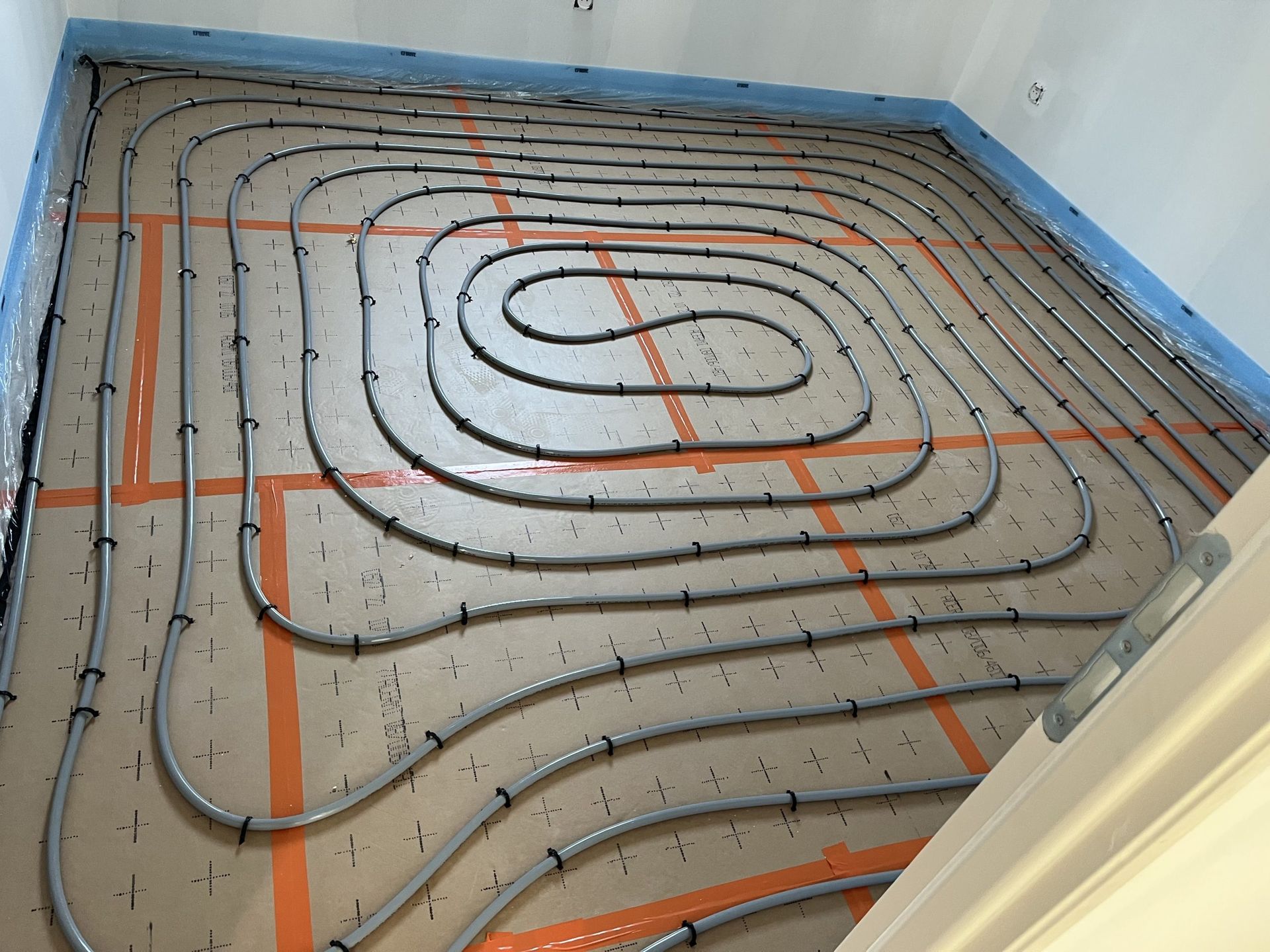 Tuyau posé sur le sol recouvrant toute la surface de la pièce.