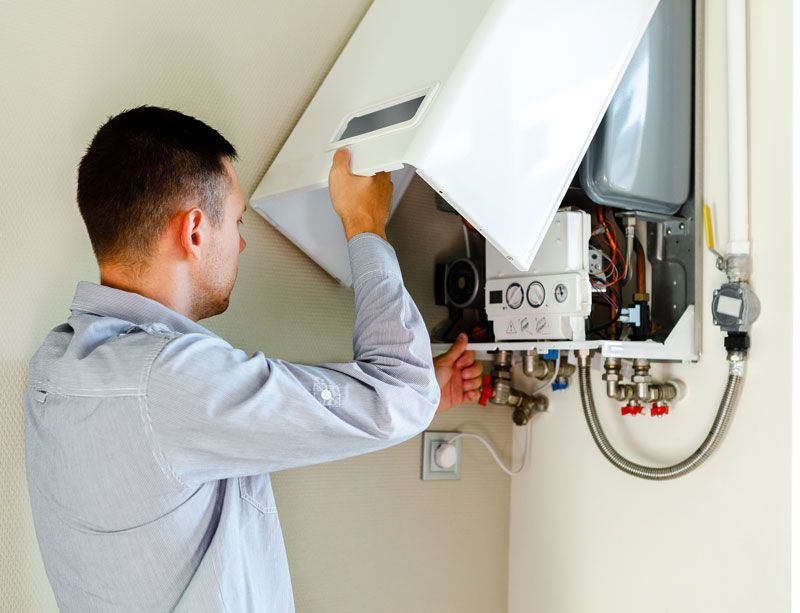 Un homme soulève le capot d'une chaudière à gaz.