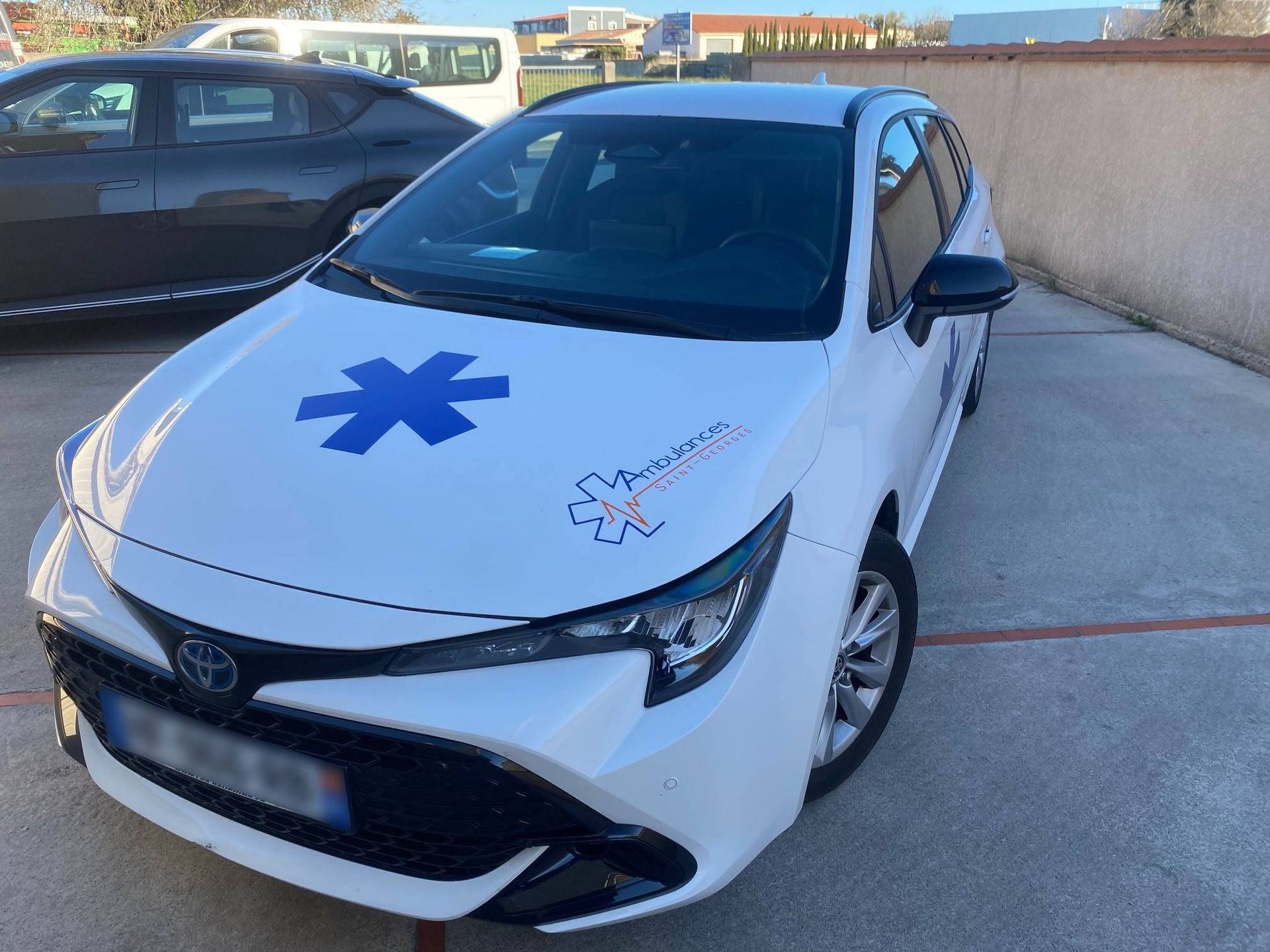 Voitures stationnées devant un bâtiment portant l'inscription Ambulances Saint-Georges.