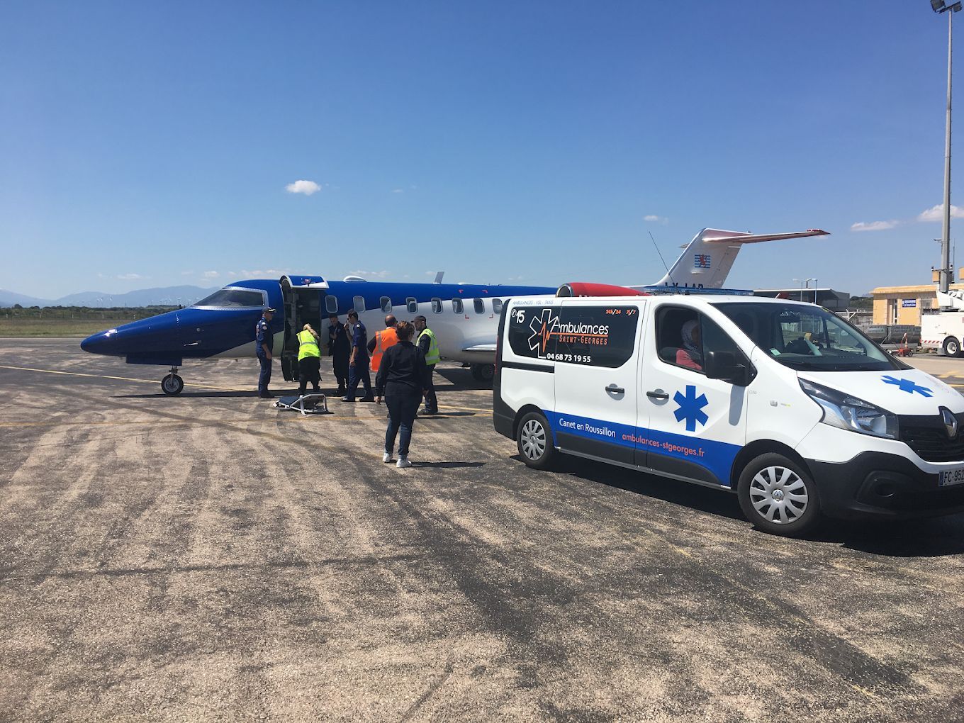 Avion et ambulance sur le tarmac ; personnel médical rassemblé près de l'avion.