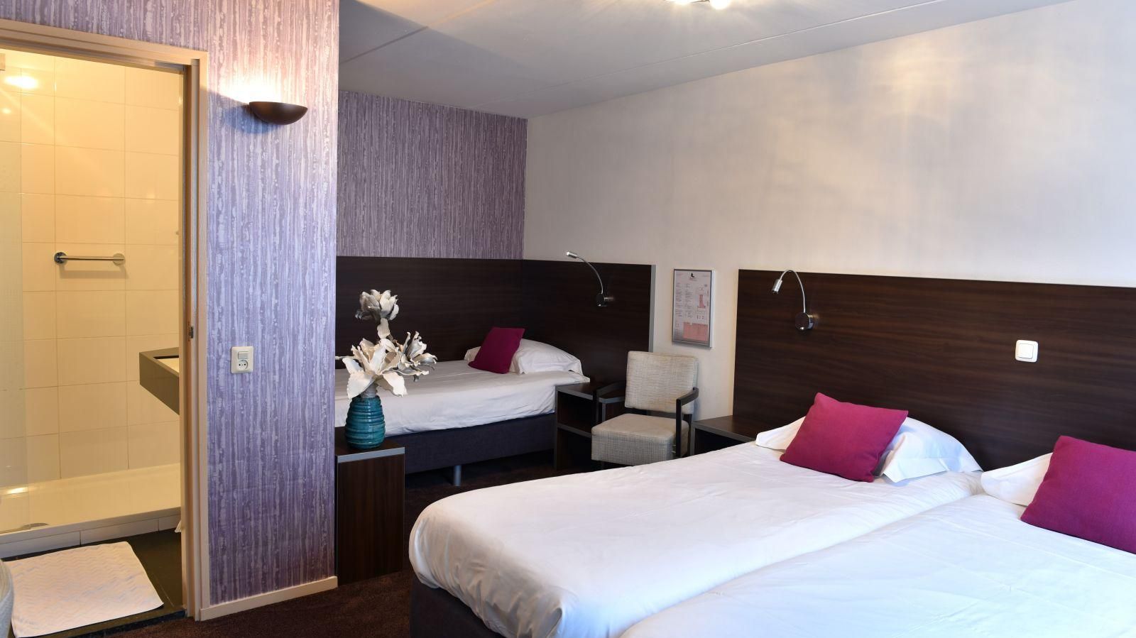 Een hotelkamer met twee bedden en een badkamer.