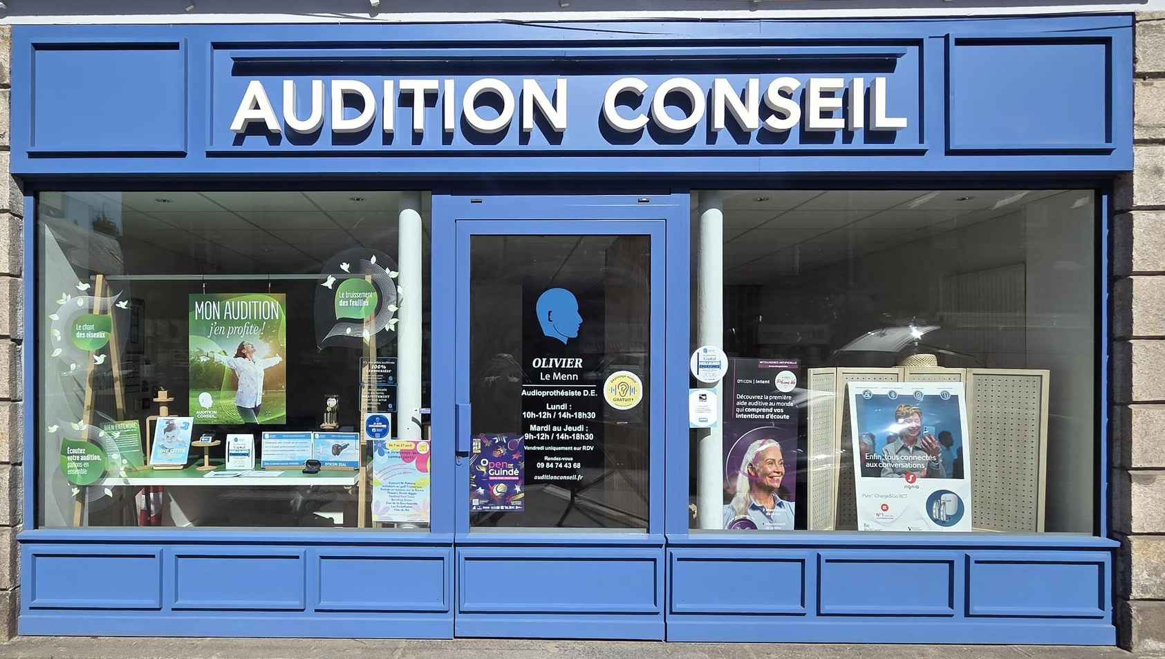 Devanture de magasin Audition Conseil avec façade bleue et vitrines donnant sur une rue.