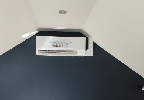Un climatiseur blanc est suspendu au plafond dans un coin d'une pièce.