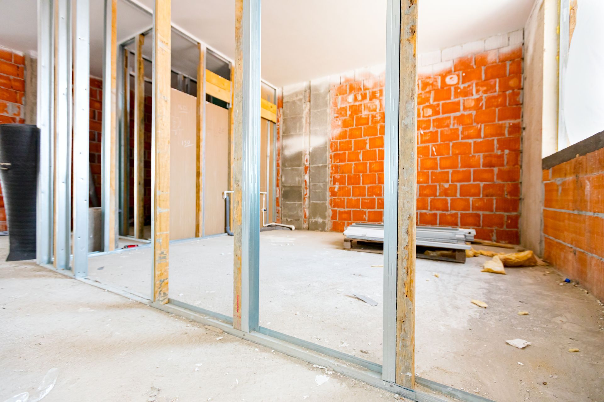 Intérieur d'une pièce en construction avec une ossature métallique, des murs en briques et un sol en béton.