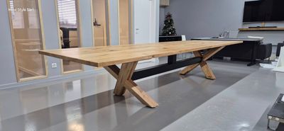 Une cuisine moderne et minimaliste avec un îlot en marbre, un parquet clair et un escalier en bois avec une rampe en verre.
