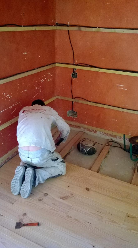 Un homme pose du parquet sur lambourdes