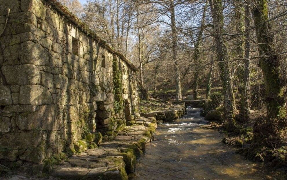 Iglesia de piedra sobre una gran formación rocosa; follaje verde, cielo nublado.