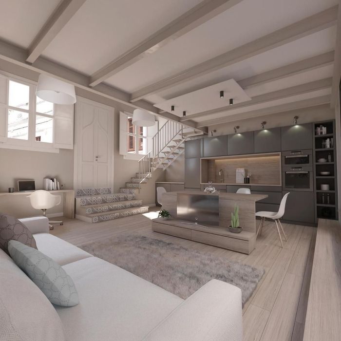 Moderno espacio diáfano con cocina, sala de estar y escalera. Presenta suelos de madera clara y decoración neutra.