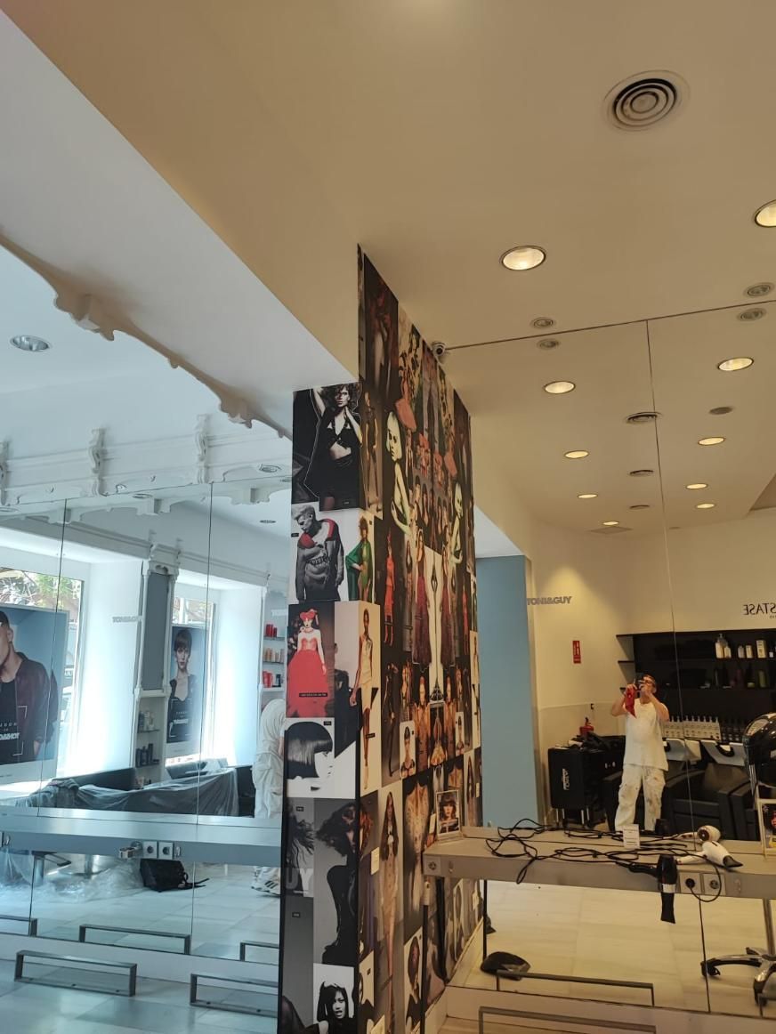 Interior de un local comercial, parcialmente renovado. Trabajadores pintan, un gran collage en la pared