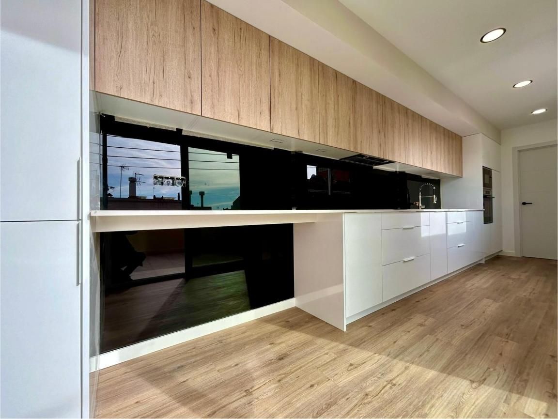 Cocina moderna con gabinetes superiores de madera clara, gabinetes inferiores blancos