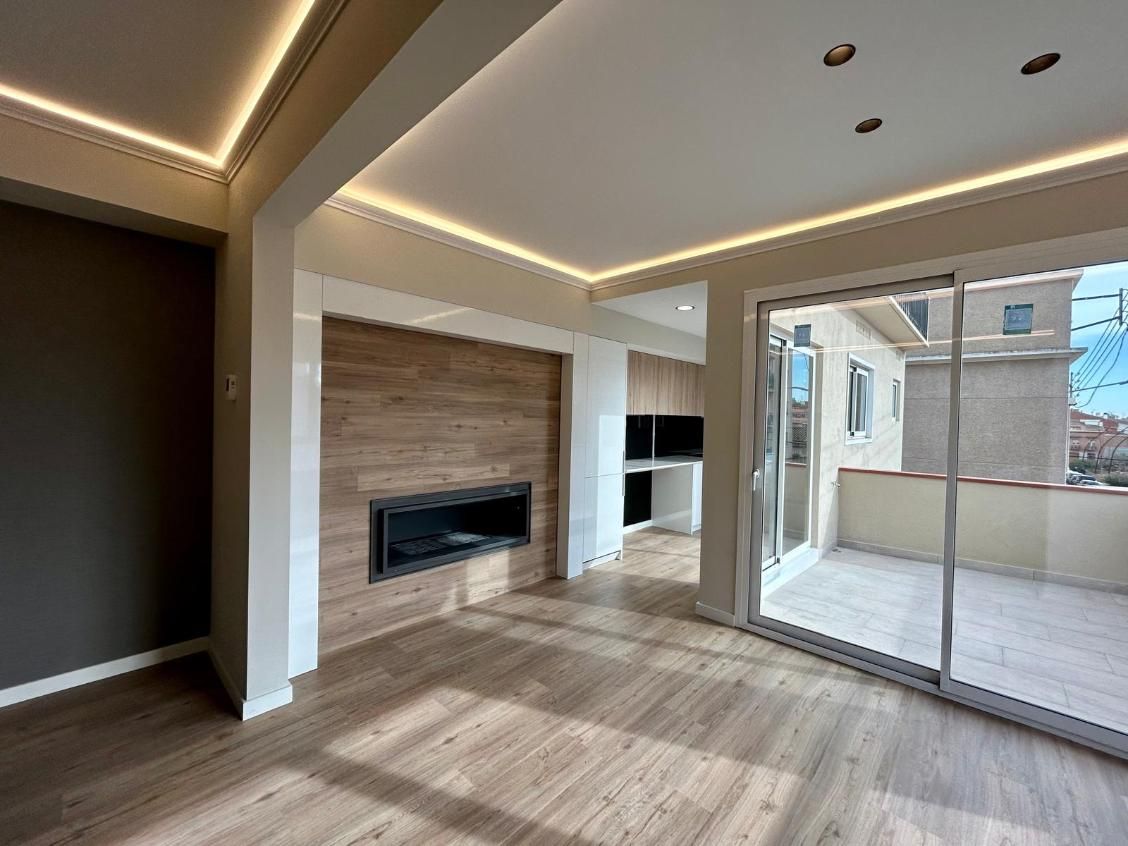 Moderna sala de estar con chimenea, pisos de madera y vista al balcón.